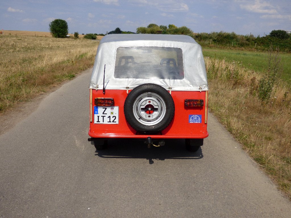 Rückansicht des Inter Trab Forstkübel "Super Trabi" mit geschlossenem Verdeck auf einer Straße zwischen Feldern und Wiesen.